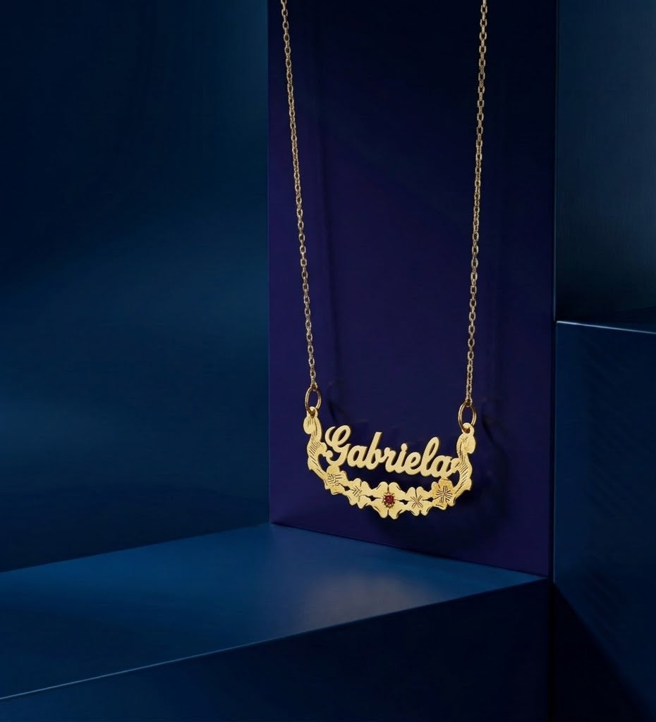 Custom gold nameplate pendant with delicate floral design and precision engraving, paired with a luxury center gemstone; a high-end jewelry piece by CustomGolds INC with a polished premium finish.