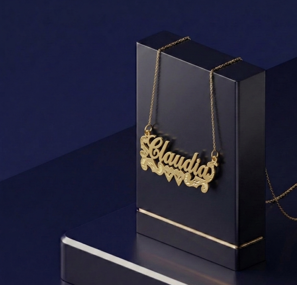 Bespoke yellow gold nameplate necklace with double heart details, crafted as a custom gold lettering pendant with soft satin and diamond-cut finish.