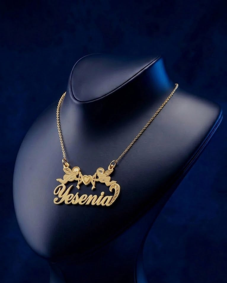 Luxury personalized nameplate necklace with twin cherub and heart design, made in 14k–18k gold options, showcasing fine custom gold lettering and premium craftsmanship.