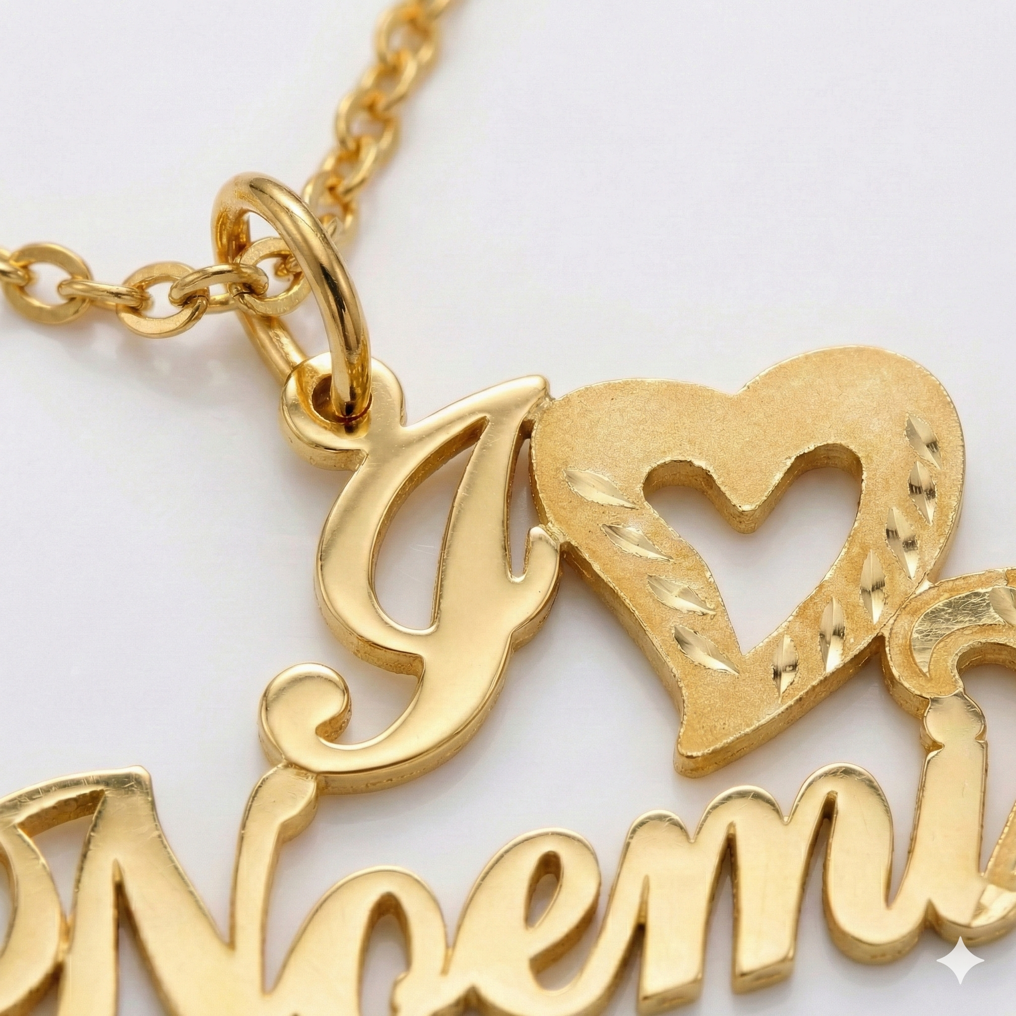 Gold necklace with heart and 'Nemi' pendant on a light background